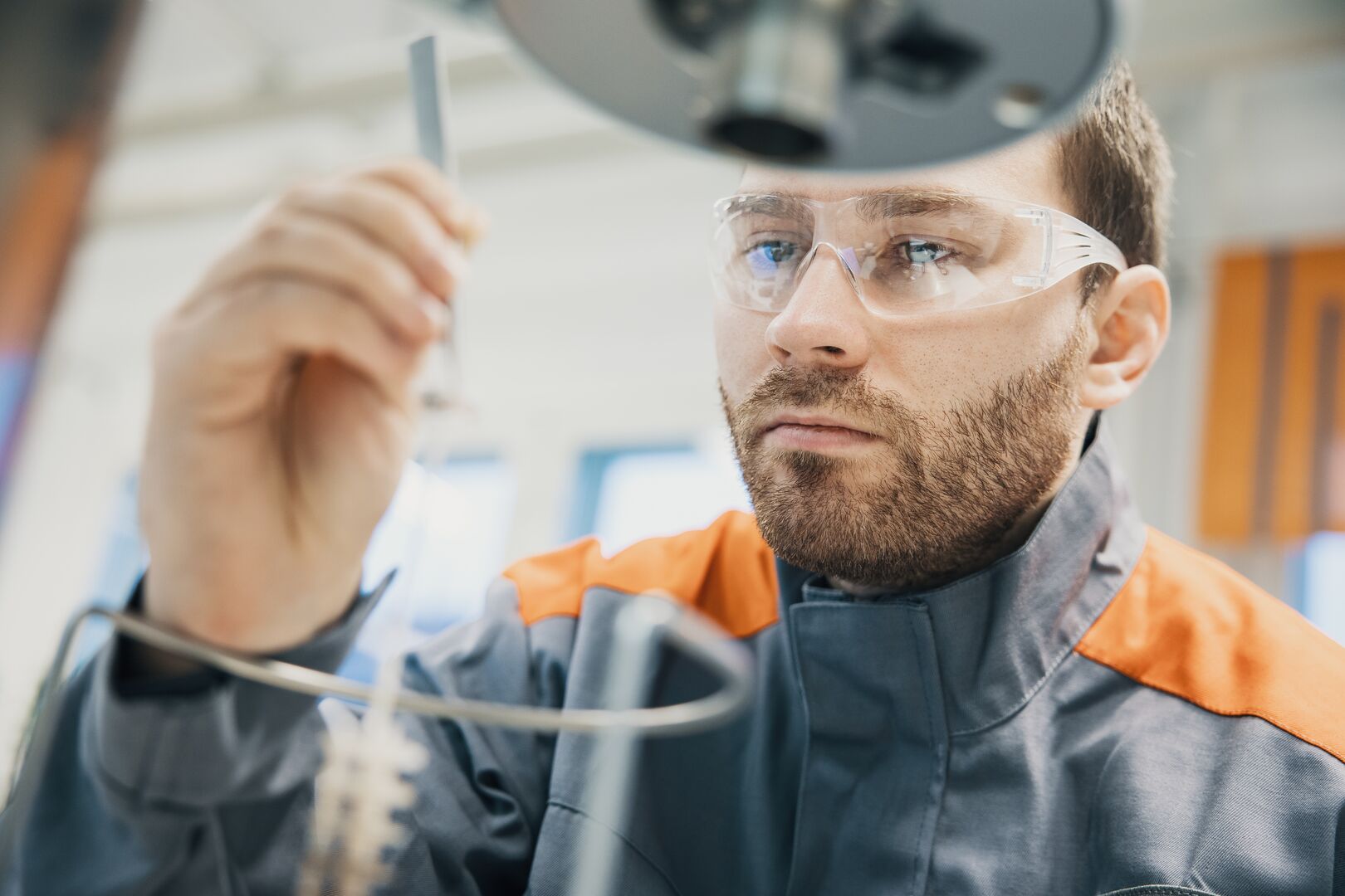 A man wearing safety goggles studying a pippet in a laboratory
