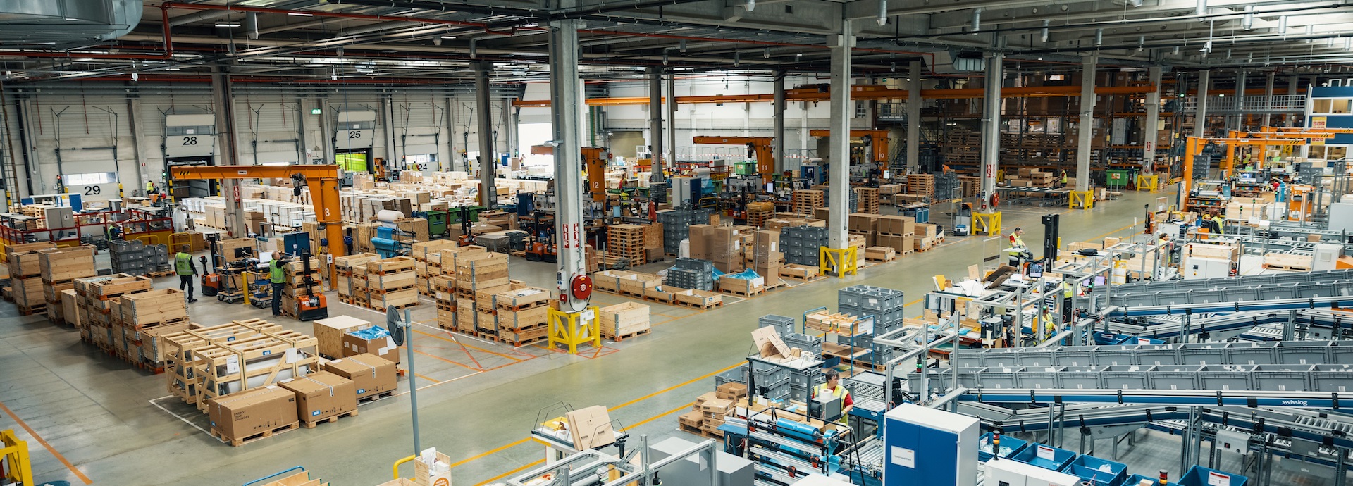 Interior view of Wärtsilä's Kampen facility in the Netherlands. Cartons, machinery and people visible.
