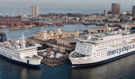 Two hospital ships from the Mercy Ships fleet in port. Mercyships.org painted on the sides.