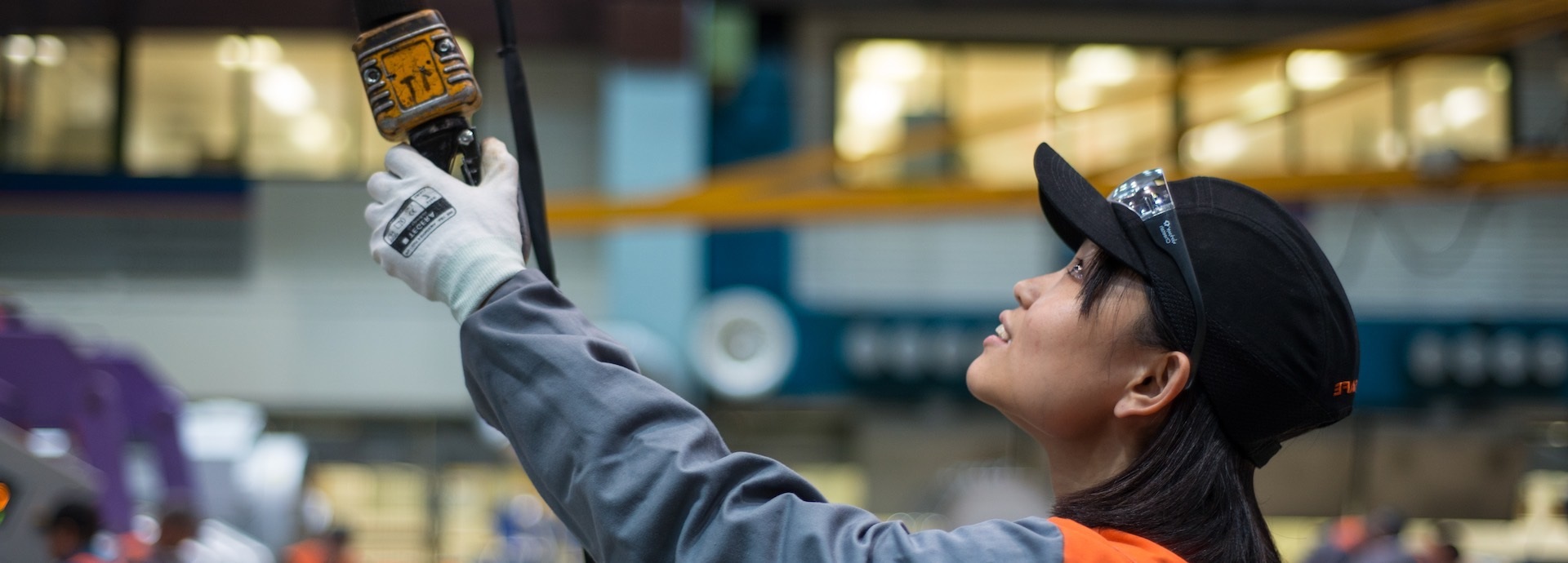Image of an Asian lady looking up at a piece of machinery she is operating