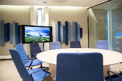 Modern co-working room. Round white table with blue chairs and one big screen on the other side of the room.