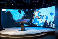 A picture from our Experience Centre. A round stage with a round touch screen behind it. Now with a huge world map.