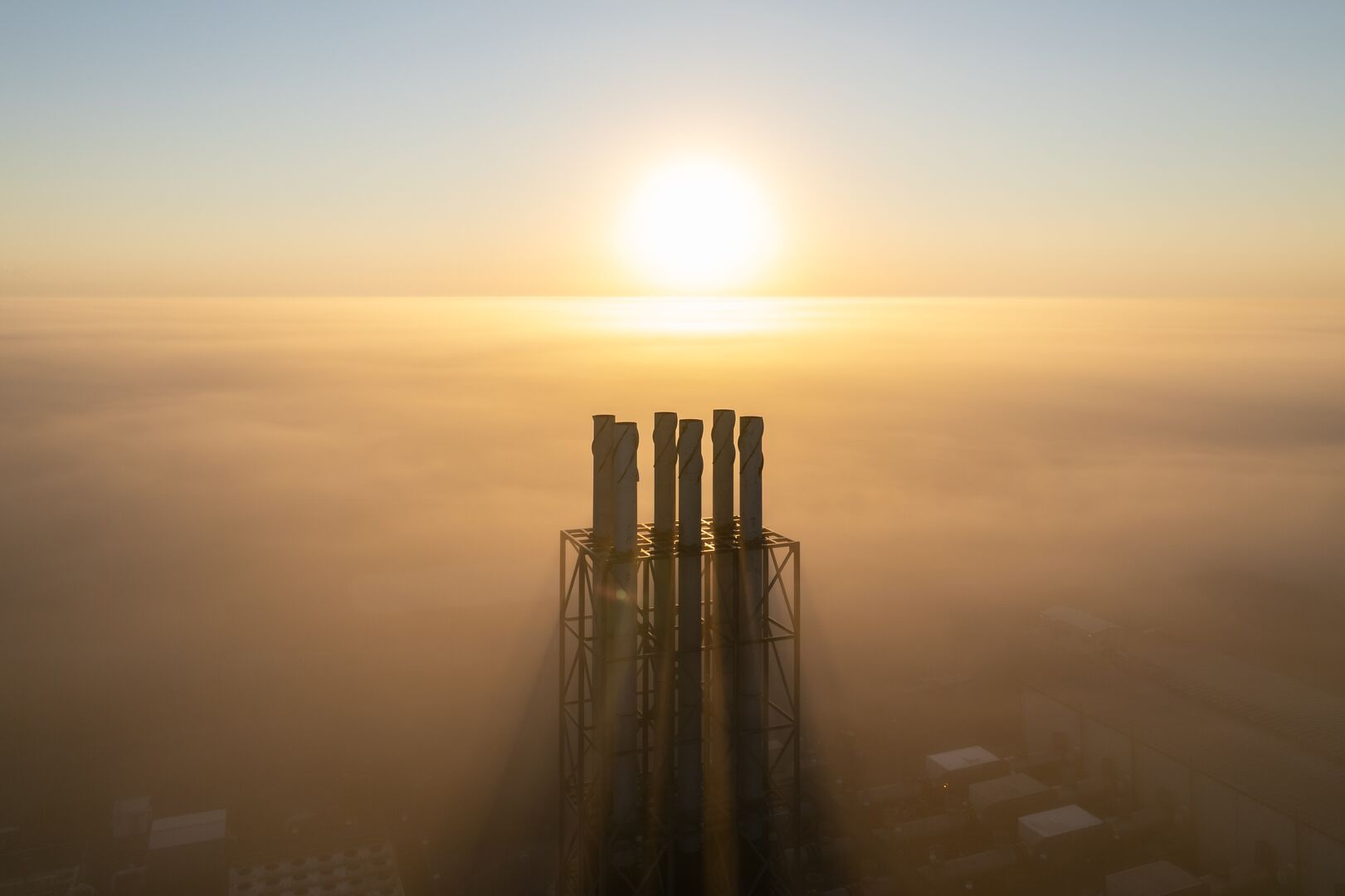 Sun shining on the stacks of a power plant