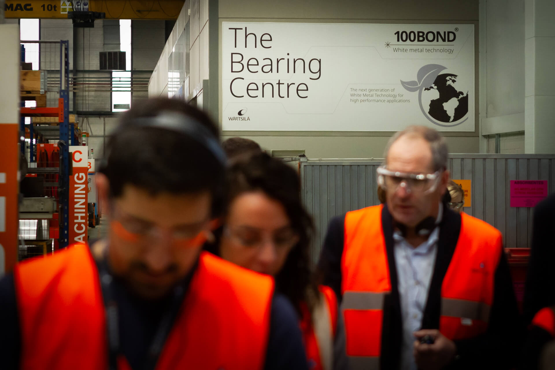 Photo of individuals in hi-vis jackets in front of The Bearing Centre banner.