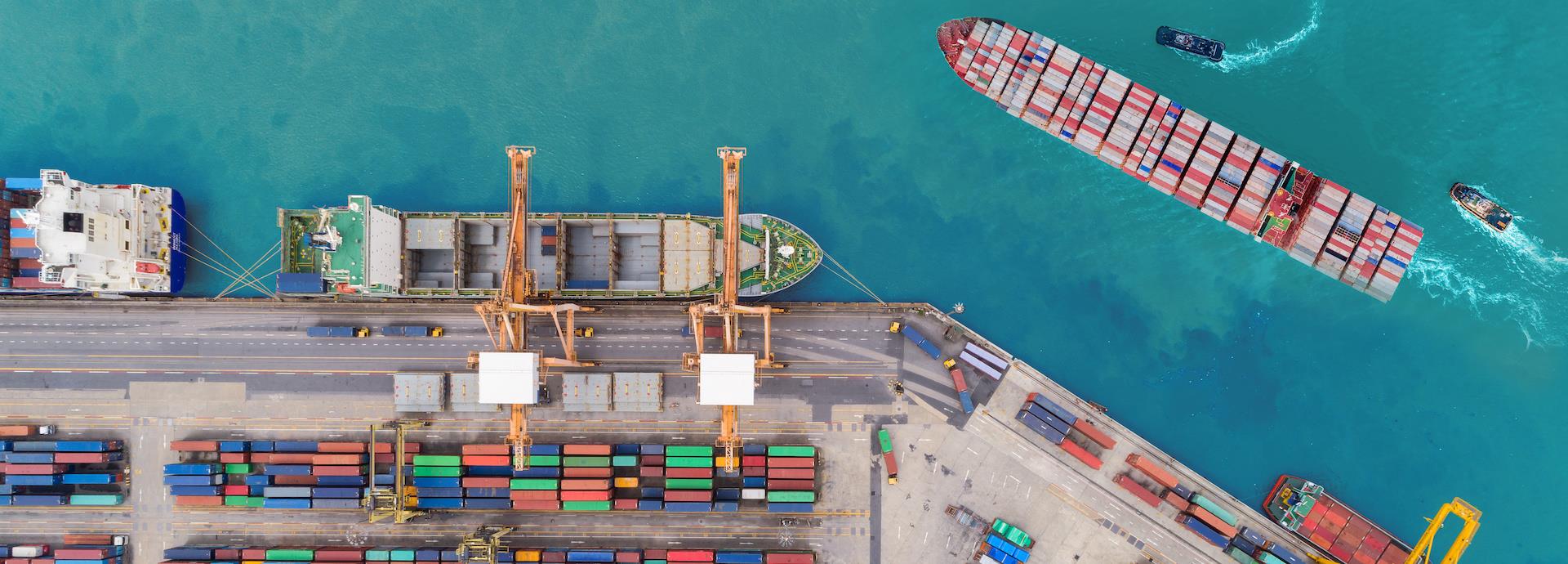 Aerial top view container ship at sea port and working crane bridge