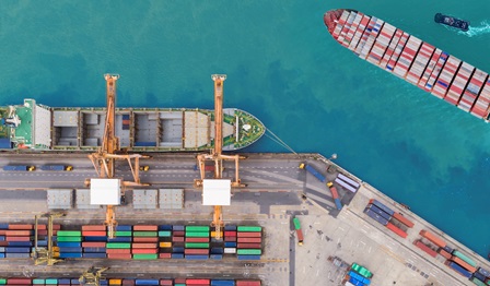 Aerial top view container ship at sea port and working crane bridge