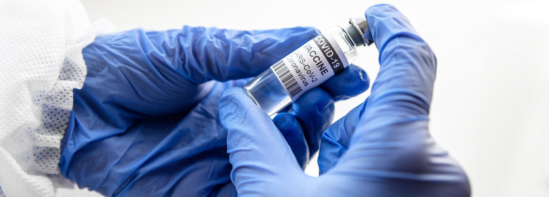 gloved hands holding a vial of vaccine